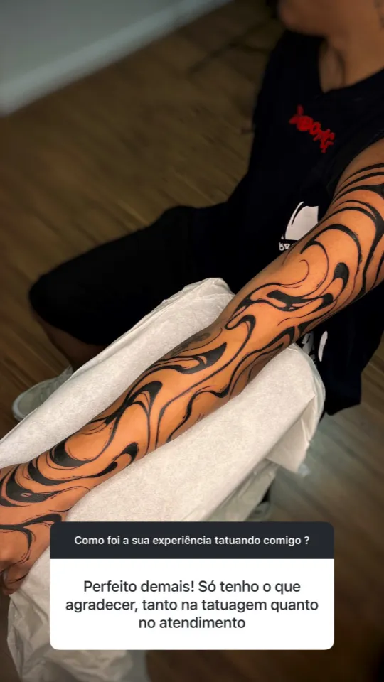 Tatuagem blackwork de linhas fluidas no braço inteiro. Depoimento: “Perfeito demais! Só tenho o que agradecer, tanto na tatuagem quanto no atendimento.”