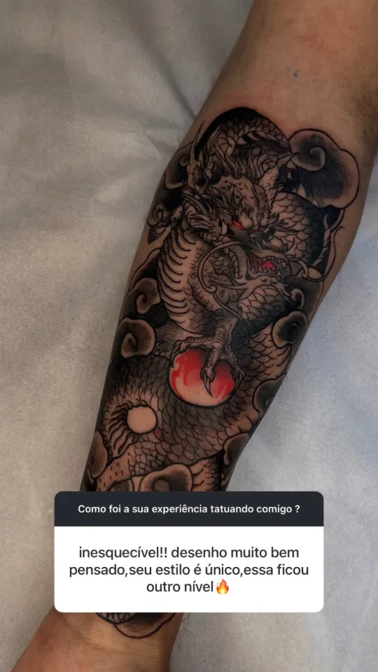 Dragão oriental segurando uma pérola vermelha, no antebraço. Depoimento: “Inesquecível!! Desenho muito bem pensado, seu estilo é único, essa ficou outro nível.”