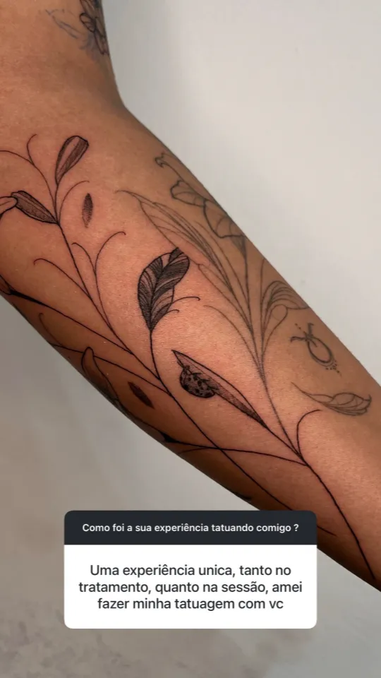 Ramos de folhas em traço fino no braço. Depoimento: “Uma experiência única, tanto no tratamento quanto na sessão, amei fazer minha tatuagem com você.”